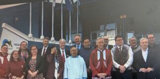 group of over a dozen people standing together with PM in middle